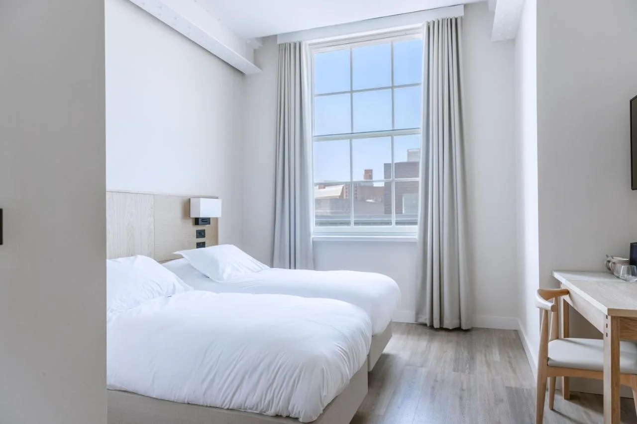 two beds in a white room with a window at School Lane Hotel in Liverpool ONE in Liverpool